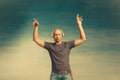 Cool bald man in a gray T-shirt and jeans jumping and fooling around and dancing in headphones on a blue background
