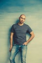 Cool bald man in a gray T-shirt posing holds his hands in his pockets against Royalty Free Stock Photo