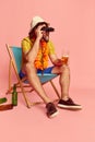 Cool beachgoer. Man in summer shirt and short with Hawaiian flower garland on chest posing over pink background. Leisure Royalty Free Stock Photo