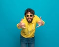 Cool bearded man in yellow hoodie making telephone gesture Royalty Free Stock Photo