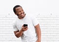 Cool black guy smiling with cellphone against white wall Royalty Free Stock Photo