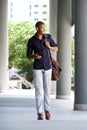 Cool black guy walking in the city with mobile phone and bag Royalty Free Stock Photo