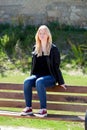 Cool blonde girl sitting on a wooden bench
