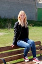Cool blonde girl sitting on a wooden bench