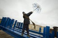 Cool boy in a coat and hat with a scarf posing plays and walks through pipes with an umbrella in an industrial area Royalty Free Stock Photo