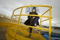 Cool boy in a coat and hat with a scarf posing plays and walks through pipes with an umbrella in an industrial area Royalty Free Stock Photo