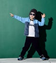 Cool boy in sunglasses, hat, fleece jacket and pants holding something in his is pointing the direction with the other Royalty Free Stock Photo