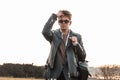 Cool brutal young man hipster in vintage sunglasses in fashion oversized black leather jacket in a shirt straightens stylish Royalty Free Stock Photo