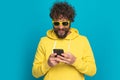 Cool casual man with long beard and moustache holding phone and texting Royalty Free Stock Photo