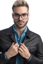 Cool casual man pulling leather jacket and wearing eyeglasses Royalty Free Stock Photo
