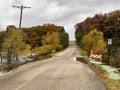 Lake flooding onto the road with traffic barricades and No Parking Any Time sign on an autumn day.