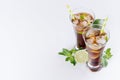 Cool cocktail rum and cola in glasses with bubbles, ice cubes, lime, leaf mint on soft light white background with copy space. Royalty Free Stock Photo