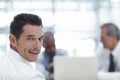 Cool and confident at work. Handsome businessman looking over his shoulder at the camera and smiling with colleagues Royalty Free Stock Photo