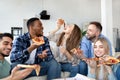 Cool diverse young friends eating pizza together, laughing and chatting at home Royalty Free Stock Photo