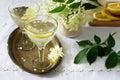 A cool drink with lemon and elderflower syrup in glasses on a metal tray. Rustic style.