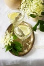 A cool drink with lemon and elderflower syrup in glasses on a metal tray. Rustic style.