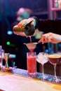 Cool Drinks. Close up of hands of bartender pouring, mixing ingredients while making cocktail alcoholic drink at the bar Royalty Free Stock Photo