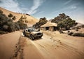 Cool dystopian comic book style image of pickup truck parked near shack in desert setting