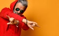 Cool elderly man with a gray beard and hair is standing with his arms crossed rock sign in red hoodie