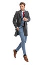 Cool elegant young man in suit with grey coat looking to side and jumping Royalty Free Stock Photo