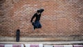 A cool, energetic Asian man is jumping outdoors, practicing his breakdance on the street