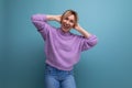 cool energetic blond young woman in purple hoodie flirting on blue background with copy space