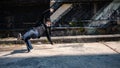 A cool, energetic Asian male hiphop dancer is practicing his b-boy breakdance on the street