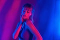 Cool fashion sexy woman standing in purple neon studio light.