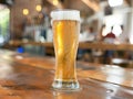 A cool, frosted glass of beer delicately rests on a rustic wooden table, creating a tranquil scene Royalty Free Stock Photo