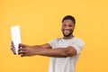 Cool game. Excited black guy holding digital tablet and looking at camera, yellow studio background