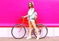 Cool girl with bicycle over colorful pink
