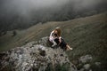 Cool Girl hug dog border collie on edge of rock in fog smiling Royalty Free Stock Photo