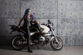 Cool girl in leather clothes near the motorcycle. Young stylish woman with colored hair on the bike. Royalty Free Stock Photo