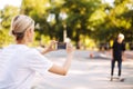 Cool girl recording new video on cellphone of young skater on skateboard for vlog spending time at modern skatepark Royalty Free Stock Photo