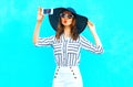 Cool girl is taking a picture on a smartphone wearing a straw hat Royalty Free Stock Photo