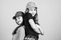 Cool girls. Sisters stand back to back beige background. Little cute girls wearing bright baseball caps. Modern fashion