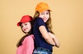Cool girls. Sisters stand back to back beige background. Little cute girls wearing bright baseball caps. Modern fashion