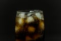 A cool glass of cola drink with ice, bubbles and fizz. Cola in glass with ice cubes isolated on dark background Royalty Free Stock Photo
