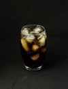 A cool glass of cola drink with ice, bubbles and fizz. Cola in glass with ice cubes isolated on dark background Royalty Free Stock Photo