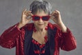 Portrait of funny happy confident senior woman in red sequin outfit and cool sunglasses Royalty Free Stock Photo