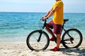 Cool guy on the beach riding mountain bike with black and red frame o over ocean background Royalty Free Stock Photo