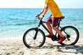 Cool guy on the beach riding mountain bike with black and red frame o over ocean background Royalty Free Stock Photo