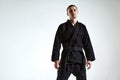 Cool guy in black kimono fighter posing in karate stance on white studio background with copy space Royalty Free Stock Photo