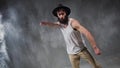 Beard guy a bboying style dancer does difficult tricks on the floor in a studio filled with flour on a black background.
