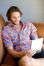 Cool guy sitting on couch with digital tablet Royalty Free Stock Photo