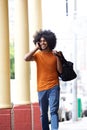 Cool guy talking on cell phone carrying bag in town Royalty Free Stock Photo