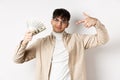 Cool handsome guy show-off his income, pointing at dollar bills and smiling boastful, making money, standing on white Royalty Free Stock Photo