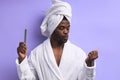 Portrait of young african man standing in towel and doing nail polish Royalty Free Stock Photo