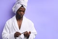 Portrait of young african man standing in towel and doing nail polish Royalty Free Stock Photo