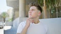 Cool, handsome young caucasian man with beard, stood in doubt on a sunny street, deep in thought, concentrating on a serious, yet Royalty Free Stock Photo